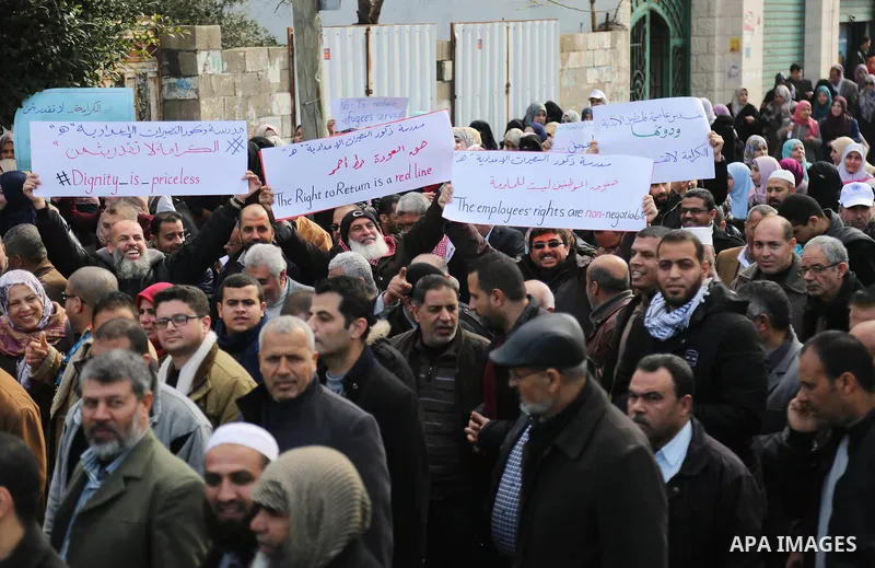 Palestinian employee of United Nations Relief and Works Agency (UNRWA) hold a sign during a protest against a U.S. decision to cut aid, in Gaza City January 29, 2018. Photo by Ashraf Amra
