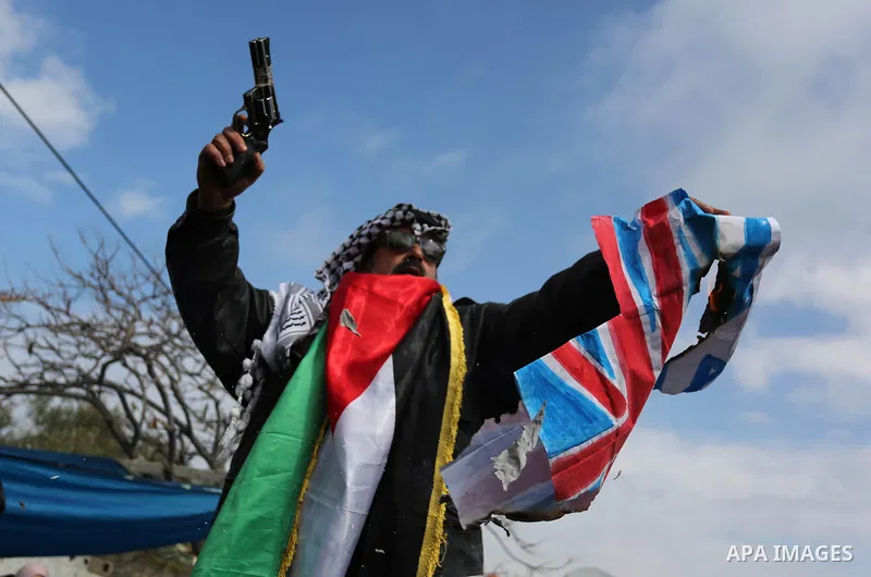 A Palestinian demonstrator gestures as he holds representations of Israeli, British and U.S. flags before burning them during a protest against a U.S. decision to cut aid, in Gaza City January 29, 2018. Photo by Ashraf A...
