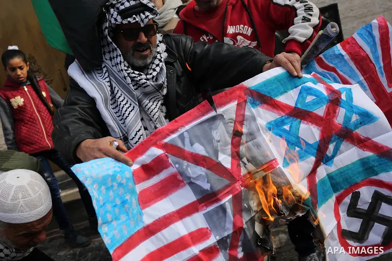 A Palestinian demonstrator burns an Israeli, British and U.S. flags during a protest in support of Palestinian teenager Ahed Tamimi, 16-year-old, in front of Red cross office, in Gaza City January 29, 2018. Photo by Ashr...