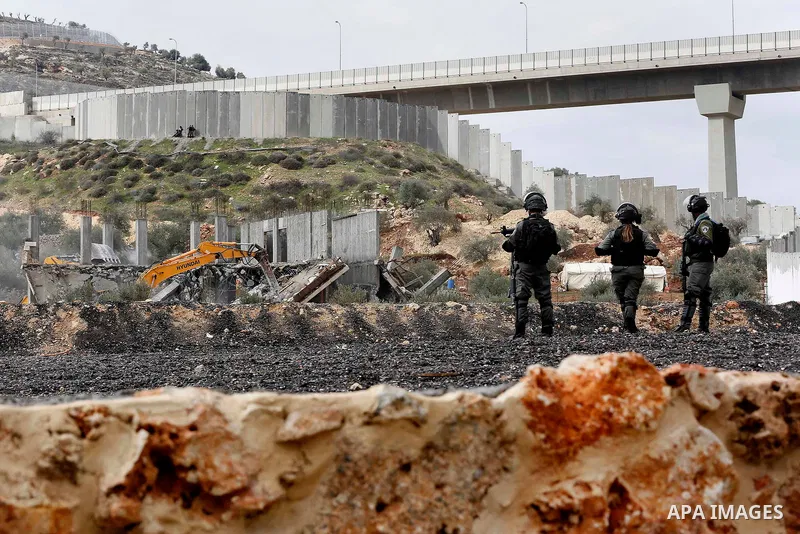 Israeli border police officers stand guard as Israeli machineries demolish an under-construction Palestinian residential building in the West Bank town of Biet Jala, near Bethlehem January 29, 2018. Photo by Wisam Hashla...