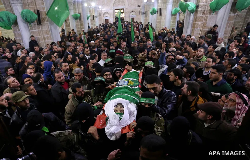 Palestinian militants from the Ezzedine al-Qassam Brigades, the armed wing of the Hamas movement carry the body of Hamas senior leader Imad al-Alami during his funeral at the al-Omari mosque in Gaza City on January 30, 2...