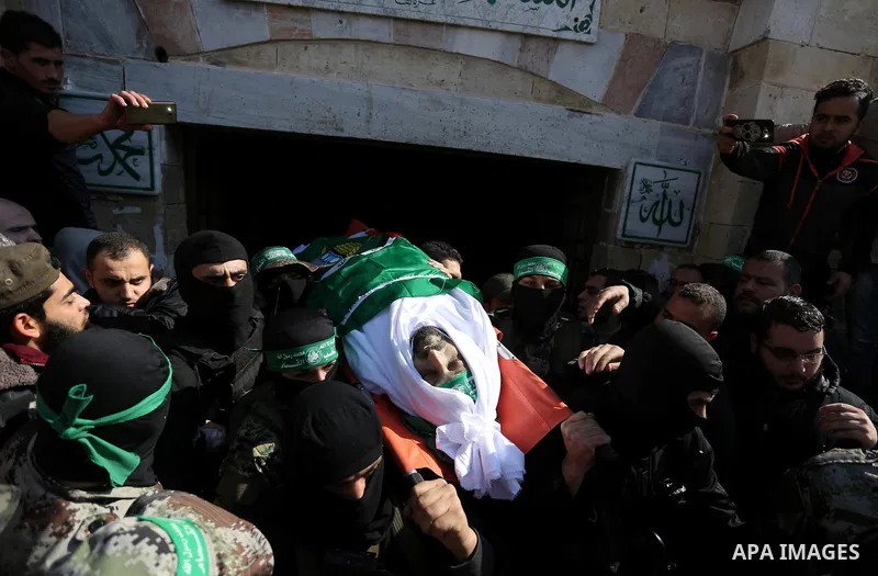Palestinian militants from the Ezzedine al-Qassam Brigades, the armed wing of the Hamas movement carry the body of Hamas senior leader Imad al-Alami during his funeral outside the al-Omari mosque in Gaza City on January...