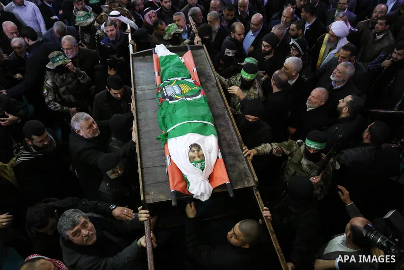 Palestinian militants from the Ezzedine al-Qassam Brigades, the armed wing of the Hamas movement carry the body of Hamas senior leader Imad al-Alami during his funeral at the al-Omari mosque in Gaza City on January 30, 2...