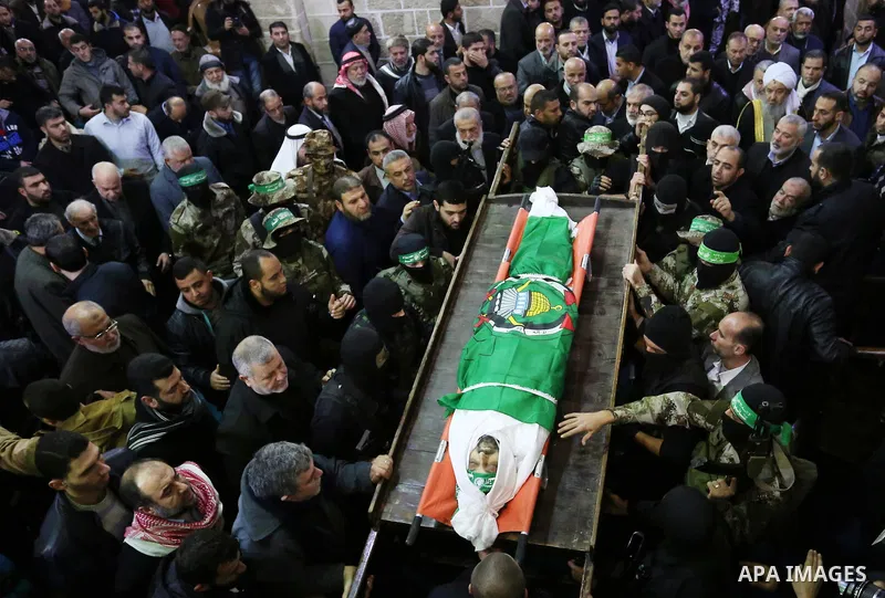 Palestinian militants from the Ezzedine al-Qassam Brigades, the armed wing of the Hamas movement carry the body of Hamas senior leader Imad al-Alami during his funeral at the al-Omari mosque in Gaza City on January 30, 2...