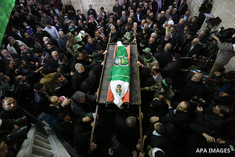 Palestinian militants from the Ezzedine al-Qassam Brigades, the armed wing of the Hamas movement carry the body of Hamas senior leader Imad al-Alami during his funeral at the al-Omari mosque in Gaza City on January 30, 2...