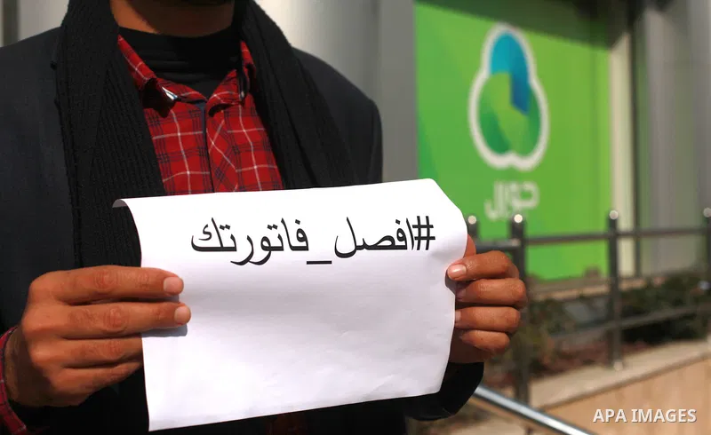 Palestinians hold banners during a protest against Jawwal's decision to add 16% VAT to its customers in the Gaza Strip in Gaza city on January 31, 2018. Photo by Mahmoud Ajour