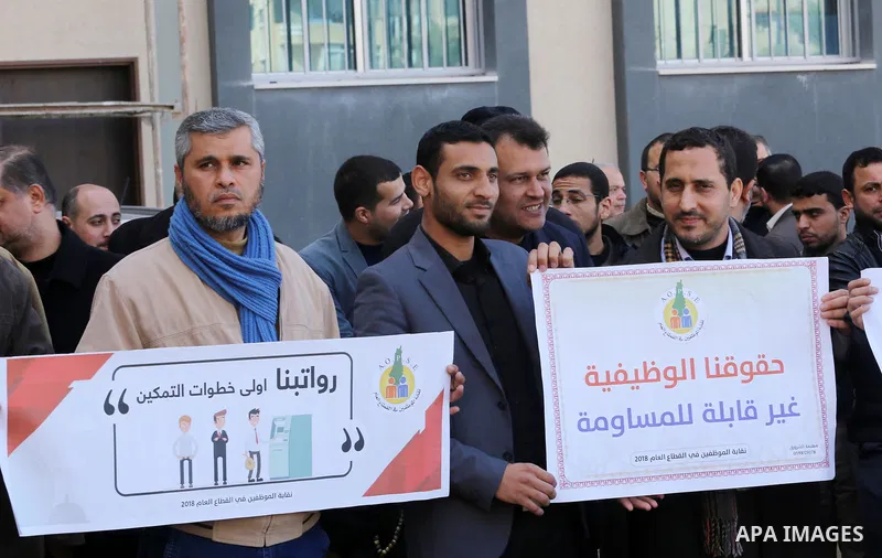 Palestinian employees of Gaza strip hold banners during a demonstration demanding their rights, in Gaza city, on January 31, 2018. Photo by Mohammed Asad