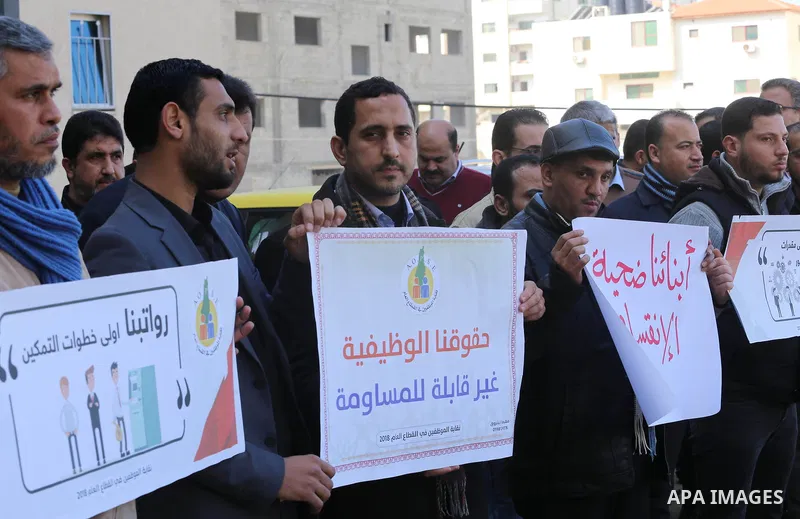 Palestinian employees of Gaza strip hold banners during a demonstration demanding their rights, in Gaza city, on January 31, 2018. Photo by Mohammed Asad