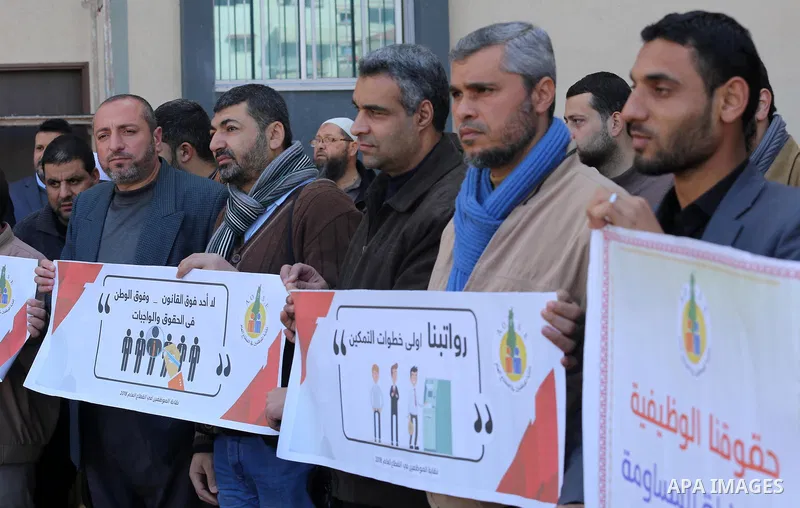 Palestinian employees of Gaza strip hold banners during a demonstration demanding their rights, in Gaza city, on January 31, 2018. Photo by Mohammed Asad