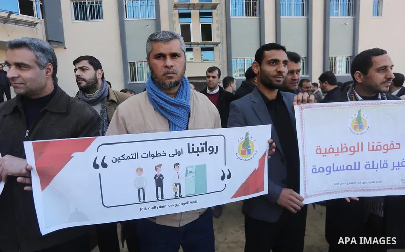 Palestinian employees of Gaza strip hold banners during a demonstration demanding their rights, in Gaza city, on January 31, 2018. Photo by Mohammed Asad