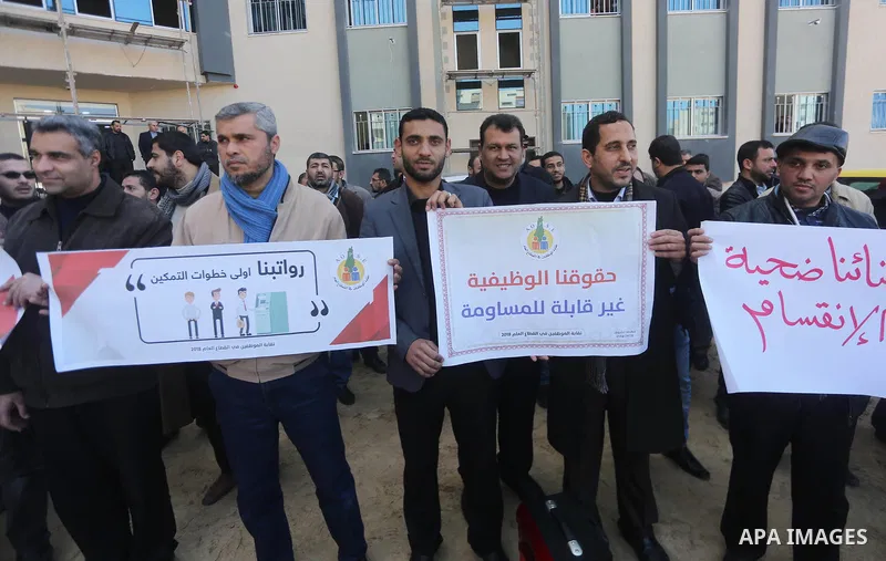 Palestinian employees of Gaza strip hold banners during a demonstration demanding their rights, in Gaza city, on January 31, 2018. Photo by Mohammed Asad