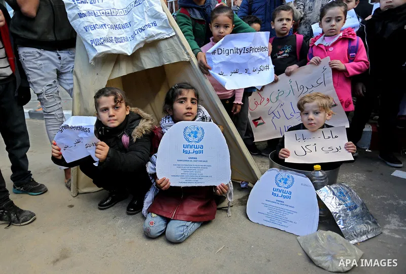 Palestinian school students shout slogans and hold placards in a protest against the US move to freeze funding for the UN agency for Palestinian refugees on January 31, 2018 at the al-Nusairat refugee camp, in central Ga...