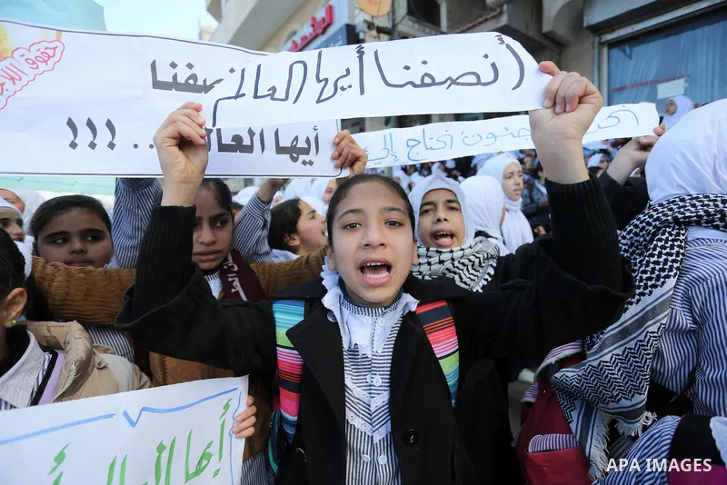 Palestinian school students shout slogans and hold placards in a protest against the US move to freeze funding for the UN agency for Palestinian refugees on January 31, 2018 at the al-Nusairat refugee camp, in central Ga...