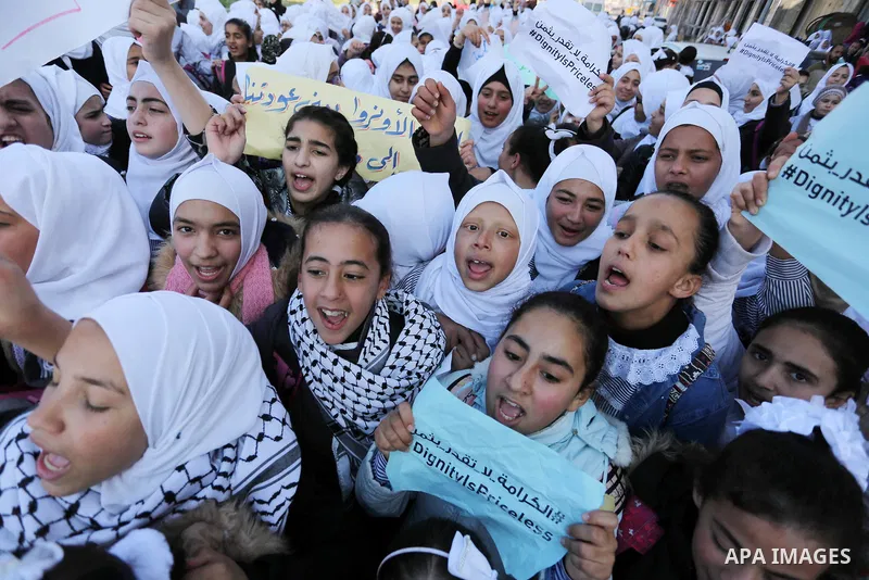 Palestinian school students shout slogans and hold placards in a protest against the US move to freeze funding for the UN agency for Palestinian refugees on January 31, 2018 at the al-Nusairat refugee camp, in central Ga...