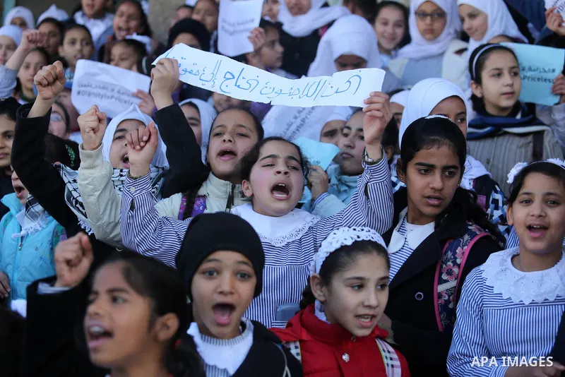 Palestinian school students shout slogans and hold placards in a protest against the US move to freeze funding for the UN agency for Palestinian refugees on January 31, 2018 at the al-Nusairat refugee camp, in central Ga...