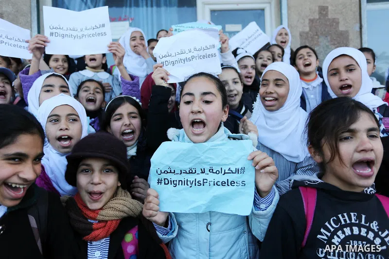 Palestinian school students shout slogans and hold placards in a protest against the US move to freeze funding for the UN agency for Palestinian refugees on January 31, 2018 at the al-Nusairat refugee camp, in central Ga...
