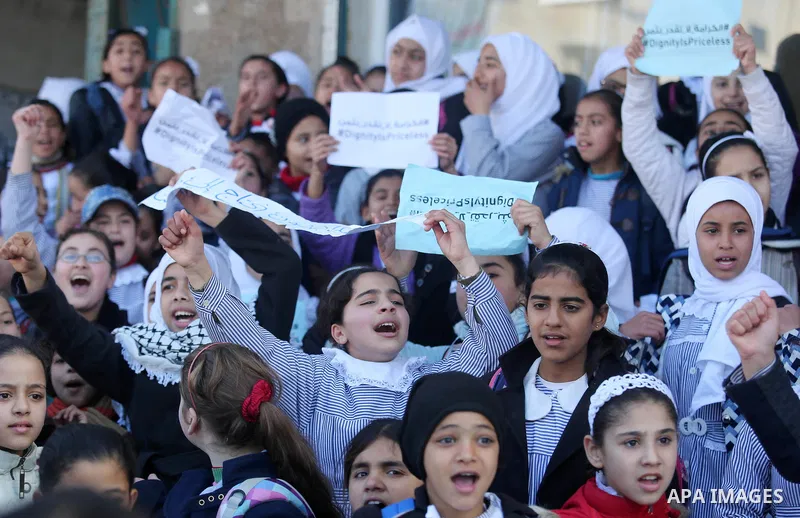 Palestinian school students shout slogans and hold placards in a protest against the US move to freeze funding for the UN agency for Palestinian refugees on January 31, 2018 at the al-Nusairat refugee camp, in central Ga...