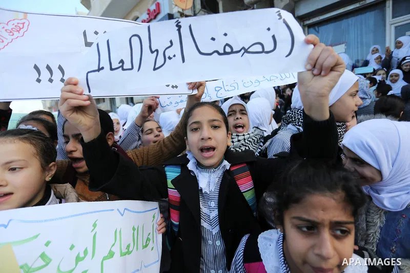 Palestinian school students shout slogans and hold placards in a protest against the US move to freeze funding for the UN agency for Palestinian refugees on January 31, 2018 at the al-Nusairat refugee camp, in central Ga...
