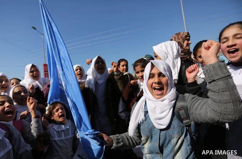 Palestinian school students shout slogans and hold placards in a protest against the US move to freeze funding for the UN agency for Palestinian refugees on January 31, 2018 at the al-Nusairat refugee camp, in central Ga...