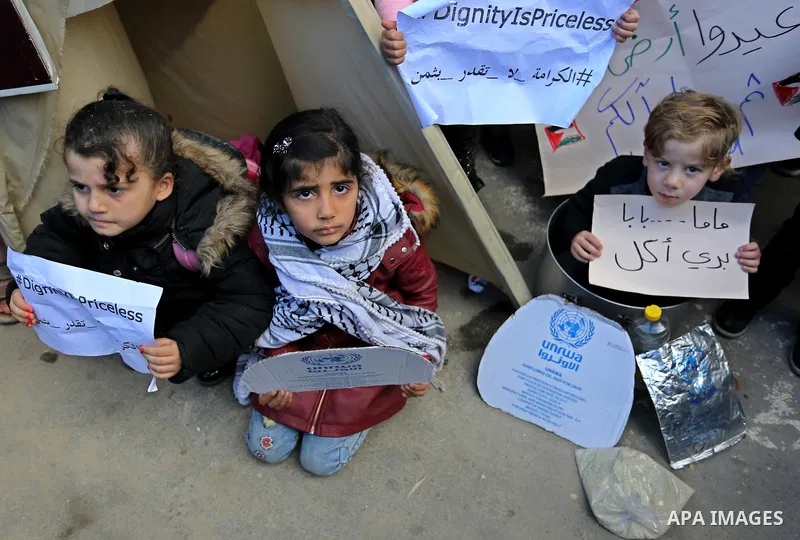 Palestinian school students shout slogans and hold placards in a protest against the US move to freeze funding for the UN agency for Palestinian refugees on January 31, 2018 at the al-Nusairat refugee camp, in central Ga...