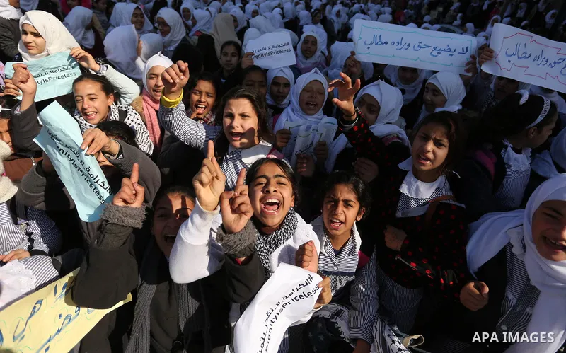 Palestinian school students shout slogans and hold placards in a protest against the US move to freeze funding for the UN agency for Palestinian refugees on January 31, 2018 at the al-Nusairat refugee camp, in central Ga...