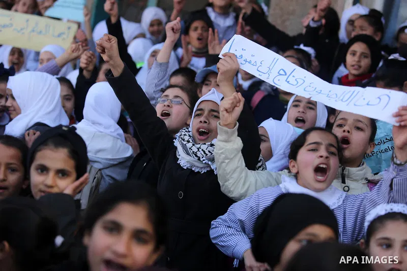 Palestinian school students shout slogans and hold placards in a protest against the US move to freeze funding for the UN agency for Palestinian refugees on January 31, 2018 at the al-Nusairat refugee camp, in central Ga...
