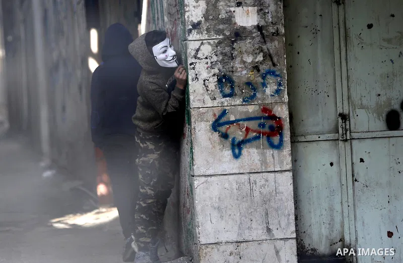 A masked Palestinian protester looks on during clashes with Israeli security forces in the West Bank city of Hebron on February 2, 2018 2018 as demonstrations continue over the US president's controversial recognition of...