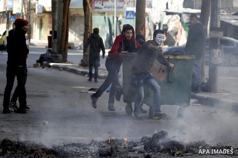 Palestinian protesters push a barricade during clashes with Israeli security forces in the West Bank city of Hebron on February 2, 2018 2018 as demonstrations continue over the US president's controversial recognition of...