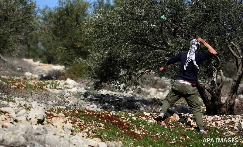 A Palestinian protester uses a slingshot to hurl stones towards Israeli security forces during clashes following a weekly demonstration against the expropriation of Palestinian land by Israel in the village of Kfar Qaddu...