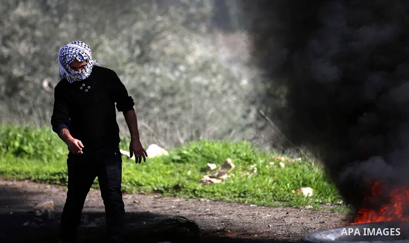 A Palestinian protester burns tires during clashes with Israeli security forces following a weekly demonstration against the expropriation of Palestinian land by Israel in the village of Kfar Qaddum, near Nablus, in the...