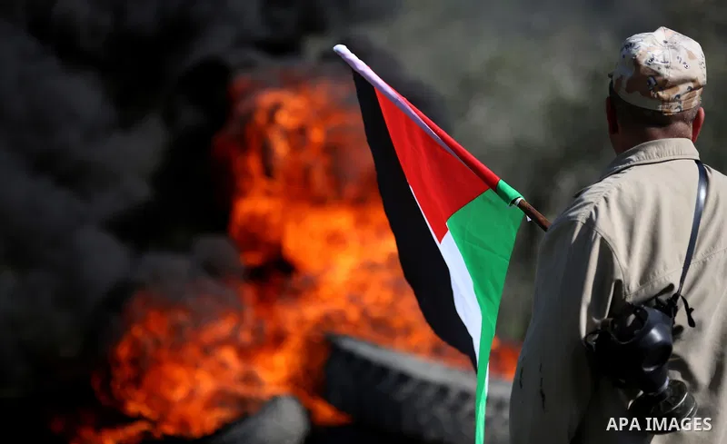 A Palestinian protester holds the national flag during clashes with Israeli security forces following a weekly demonstration against the expropriation of Palestinian land by Israel in the village of Kfar Qaddum, near Nab...