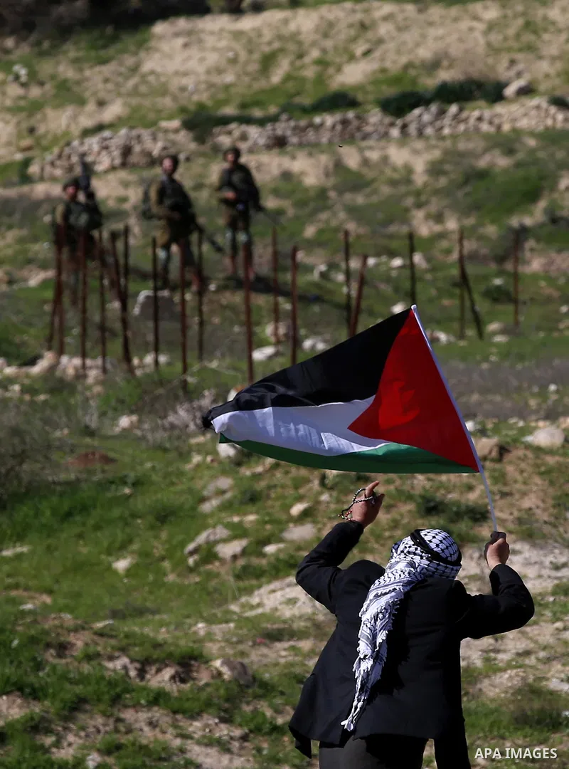 An elderly Palestinian man holds a Palestinian flag during clashes with Israeli security forces following a demonstration near the Hawara checkpoint, south of the West Bank city of Nablus on February 2, 2018, as demonstr...