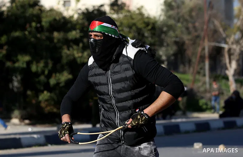 A Palestinian protester uses a slingshot to hurl stones towards Israeli security forces during clashes following a demonstration near the Hawara checkpoint, south of the West Bank city of Nablus on February 2, 2018, as d...