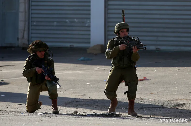 Israeli soldiers aim their weapons towards Palestinian protesters during clashes following a demonstration near the Hawara checkpoint, south of the West Bank city of Nablus on February 2, 2018, as demonstrations continue...