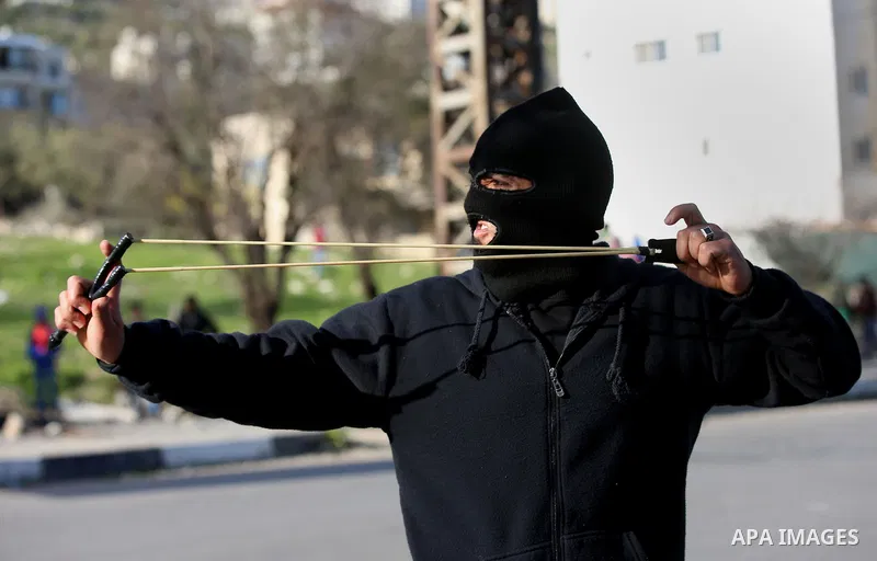 A Palestinian protester uses a slingshot to hurl stones towards Israeli security forces during clashes following a demonstration near the Hawara checkpoint, south of the West Bank city of Nablus on February 2, 2018, as d...