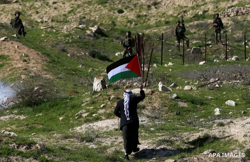 An elderly Palestinian man holds a Palestinian flag during clashes with Israeli security forces following a demonstration near the Hawara checkpoint, south of the West Bank city of Nablus on February 2, 2018, as demonstr...
