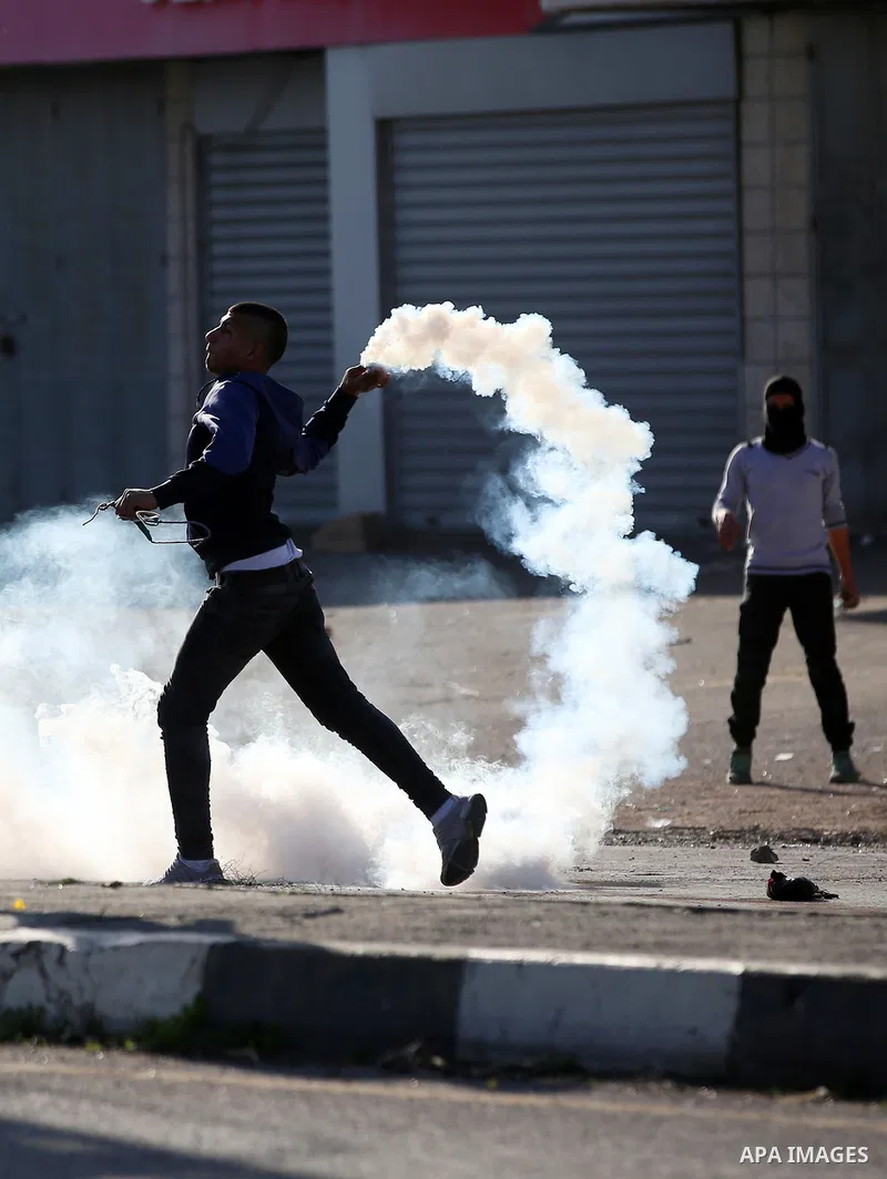A Palestinian protester throws back a teargas canister towards Israeli security forces during clashes following a demonstration near the Hawara checkpoint, south of the West Bank city of Nablus on February 2, 2018, as de...