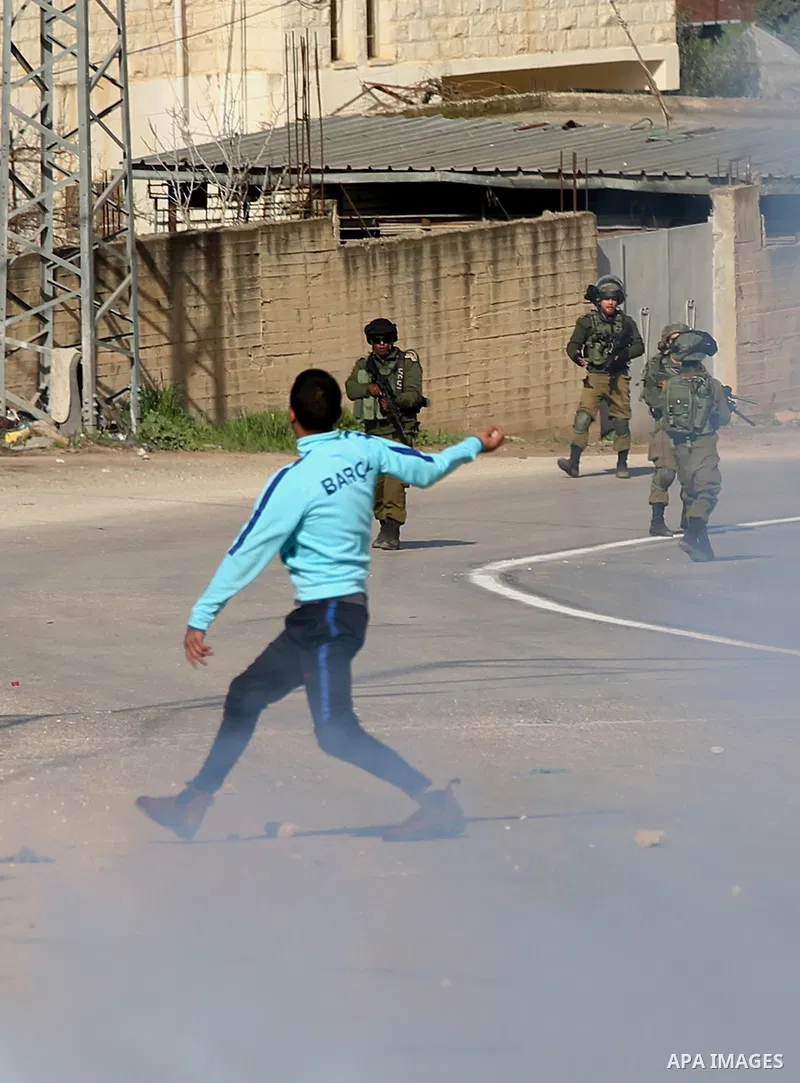 A Palestinian protester hurls stones towards Israeli security forces during a search operation for Palestinians suspected of carrying out attacks in the West Bank village of Zababdeh, north of Jenin on February 3, 2018....