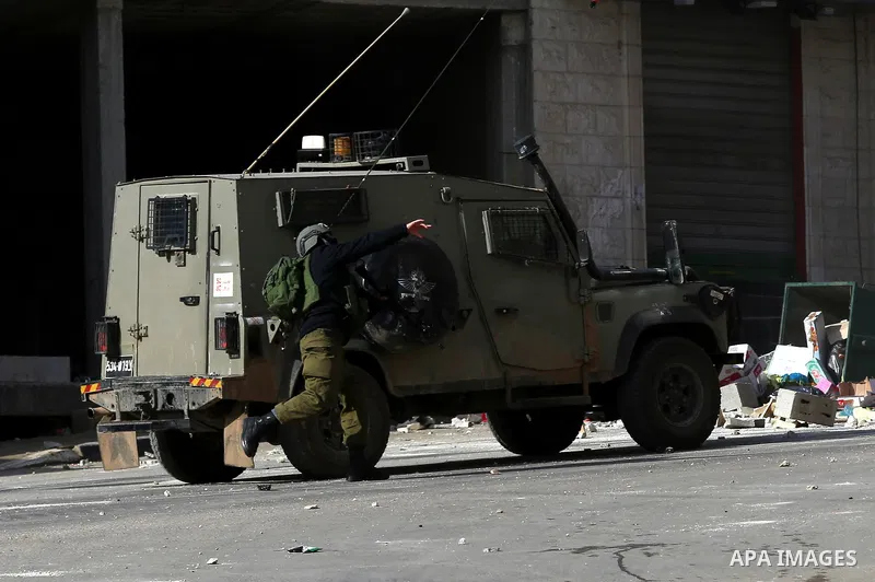 A member of Israeli security forces throws a tear gas canister towards Palestinian protesters during a search operation for Palestinians suspected of carrying out attacks in the West Bank village of Zababdeh, north of Je...