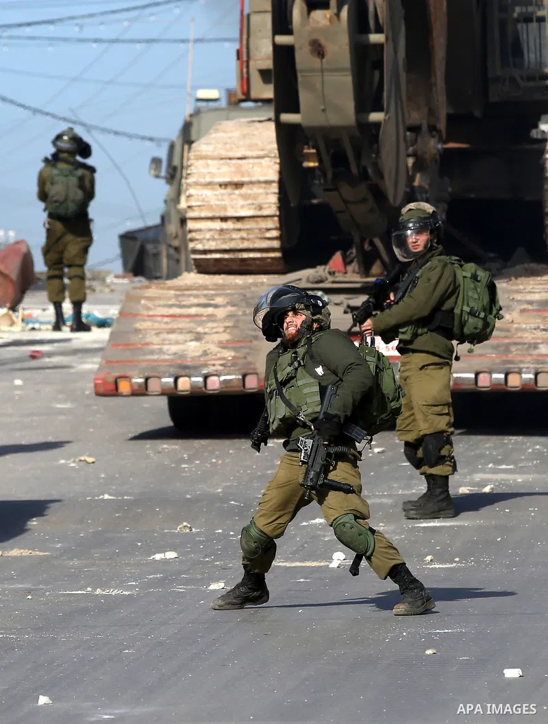 A member of Israeli security forces throws a tear gas canister towards Palestinian protesters during a search operation for Palestinians suspected of carrying out attacks in the West Bank village of Zababdeh, north of Je...