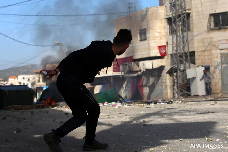 A Palestinian protester hurls stones towards Israeli security forces during a search operation for Palestinians suspected of carrying out attacks in the West Bank village of Zababdeh, north of Jenin on February 3, 2018....