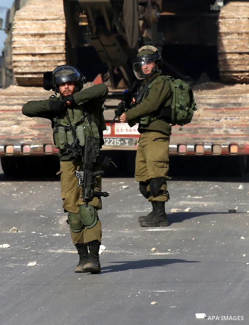 A member of Israeli security forces throws a tear gas canister towards Palestinian protesters during a search operation for Palestinians suspected of carrying out attacks in the West Bank village of Zababdeh, north of Je...