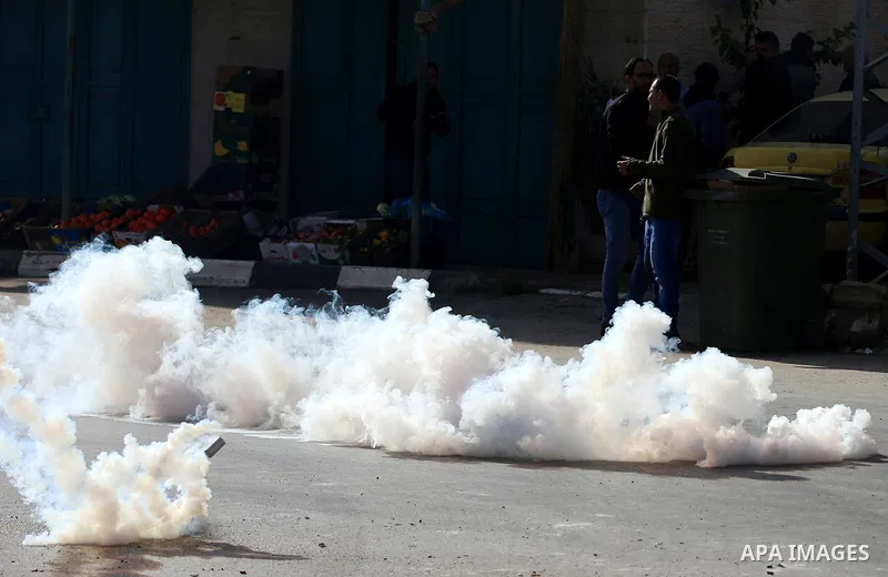 Palestinian protesters take cover form a tear gas canister fired by Israeli security forces during a search operation for Palestinians suspected of carrying out attacks in the West Bank village of Zababdeh, north of Jeni...