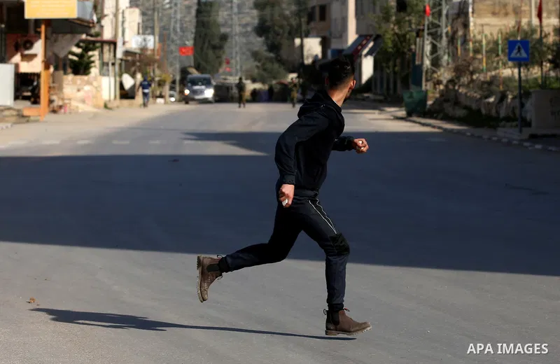 A Palestinian protester hurls stones towards Israeli security forces during a search operation for Palestinians suspected of carrying out attacks in the West Bank village of Zababdeh, north of Jenin on February 3, 2018....