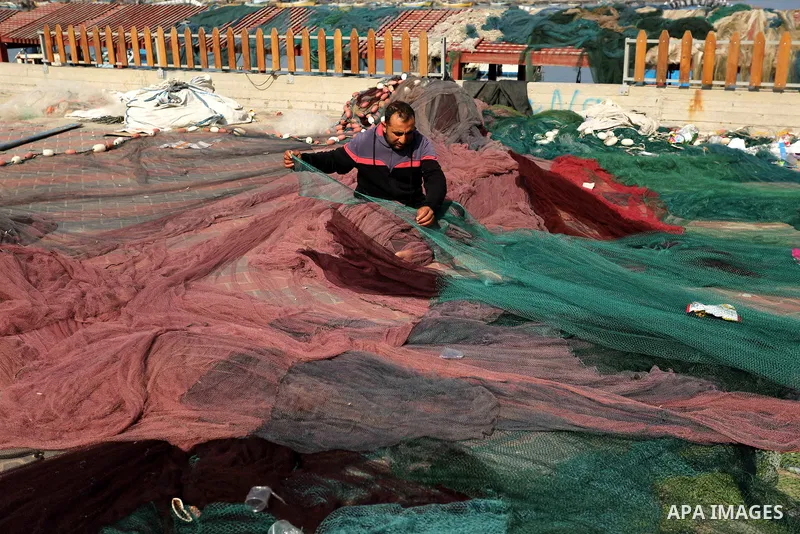 A Palestinian fisherman fixes his fishing nets during a ceremony of support Palestinian fishermen project funded by the national islamic committee for development and social solidarity, in Gaza sea port on February 3, 20...