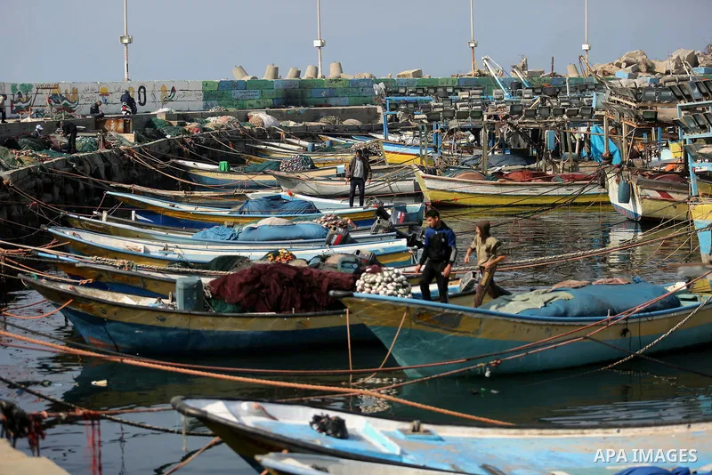 Palestinian fishermen work on their fishing boat in Gaza sea port on February 3, 2018. Photo by Ashraf Amra