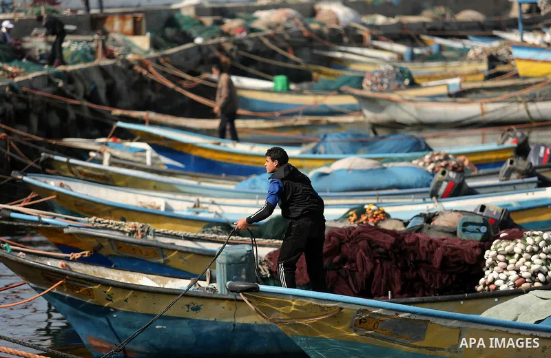 Palestinian fishermen work on their fishing boat in Gaza sea port on February 3, 2018. Photo by Ashraf Amra