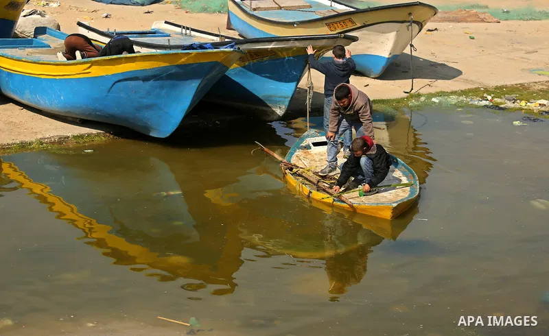 Palestinian boys play on fishing boats during a ceremony of support Palestinian fishermen project funded by the national islamic committee for development and social solidarity, in Gaza sea port on February 3, 2018. Phot...