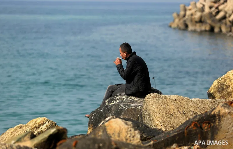 A Palestinian man sits on a rock in Gaza sea port on February 3, 2018. Photo by Ashraf Amra