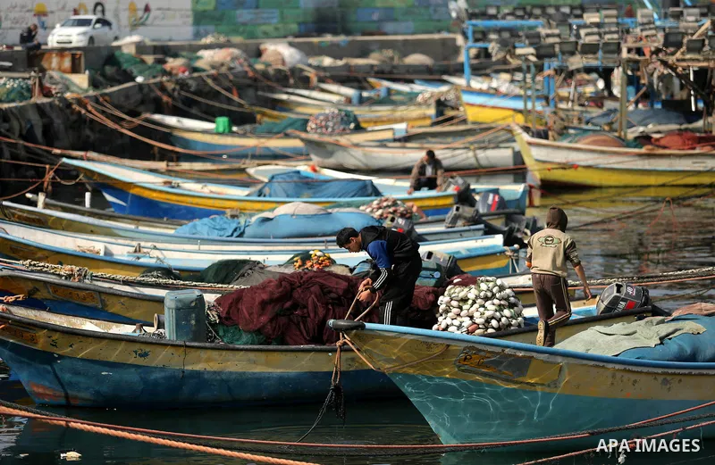 Palestinian fishermen work on their fishing boat in Gaza sea port on February 3, 2018. Photo by Ashraf Amra